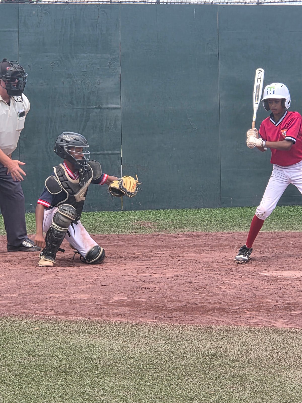 Young batter at the plate with the catcher set behind him