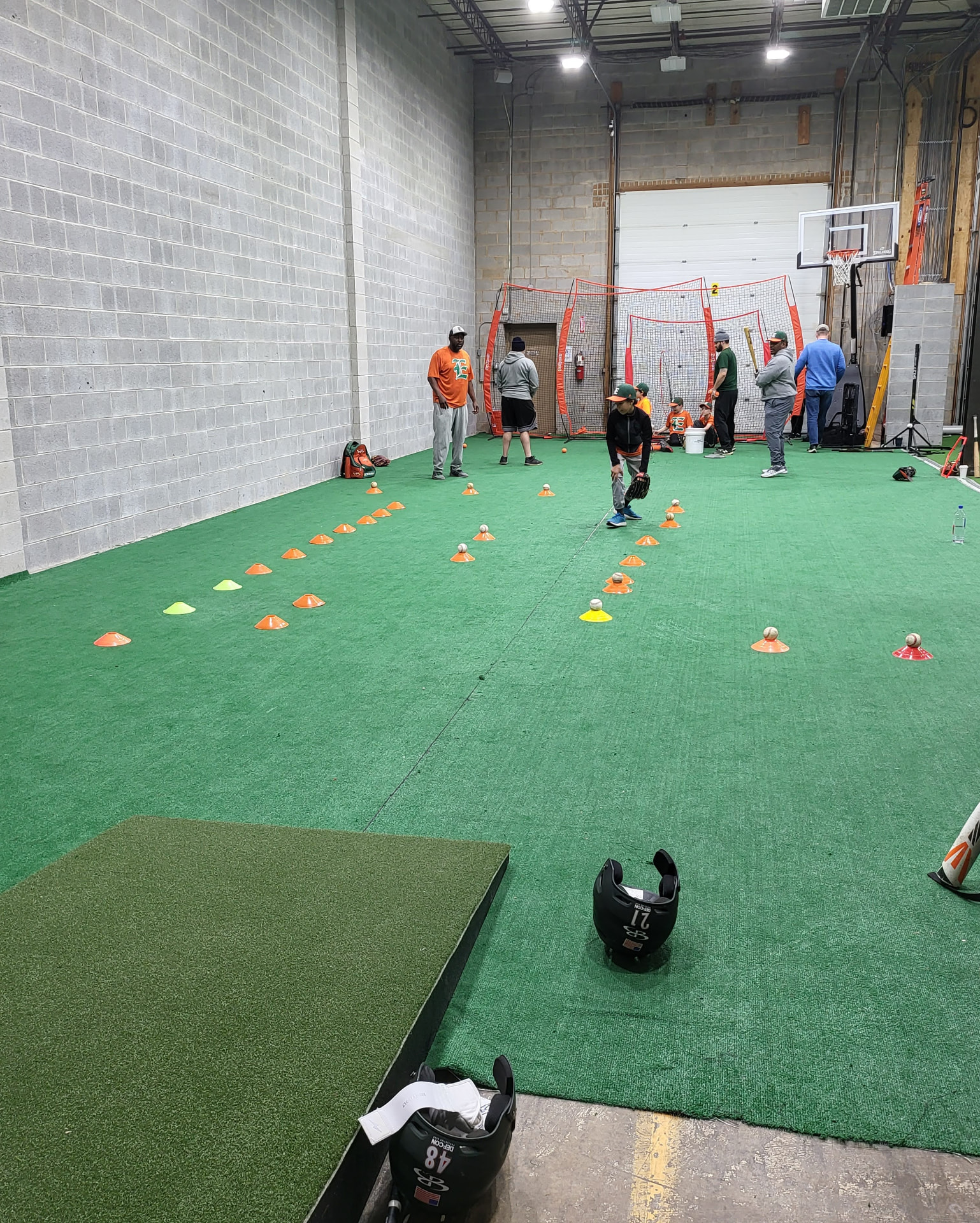 Indoor baseball practice with cones and coaches