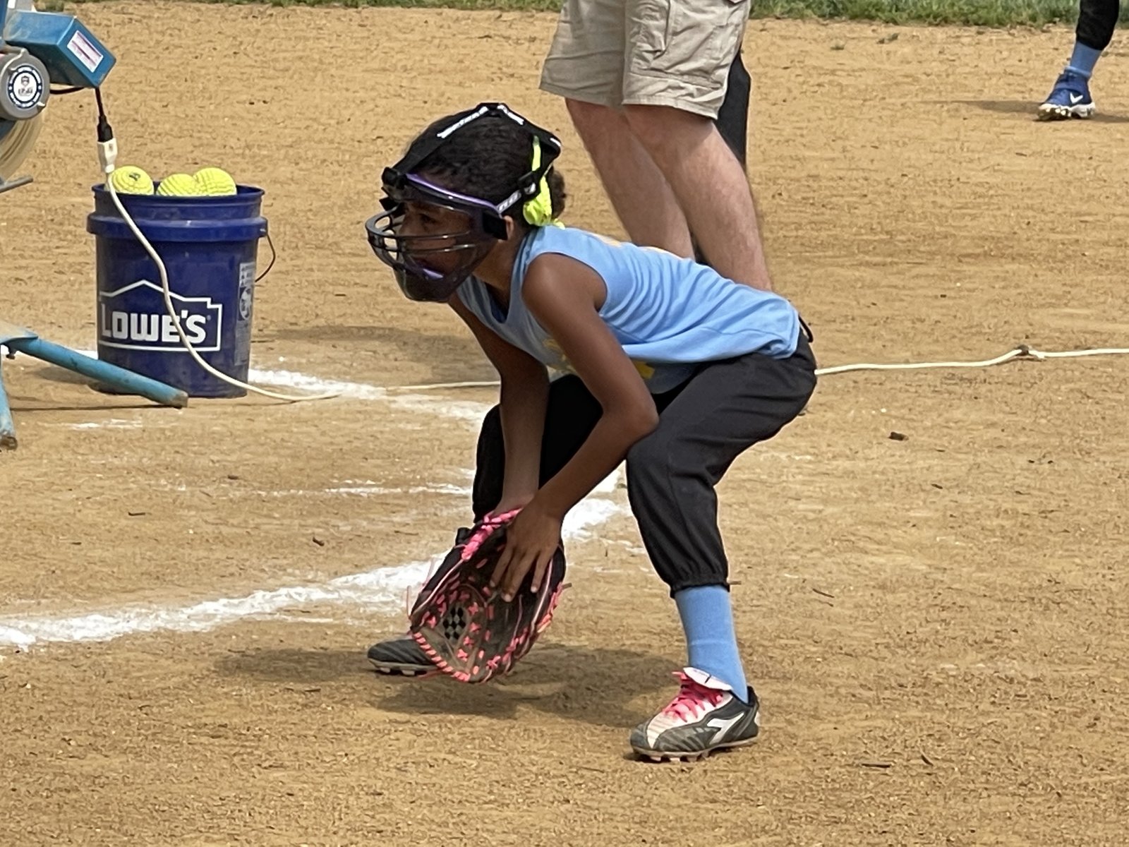 Youth softball fielder scooping a ground ball near home plate
