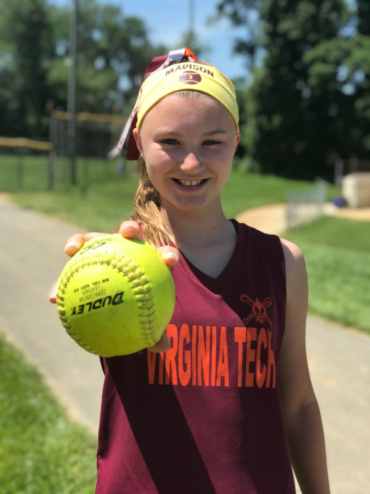 Young softball player holding up a game ball after a win