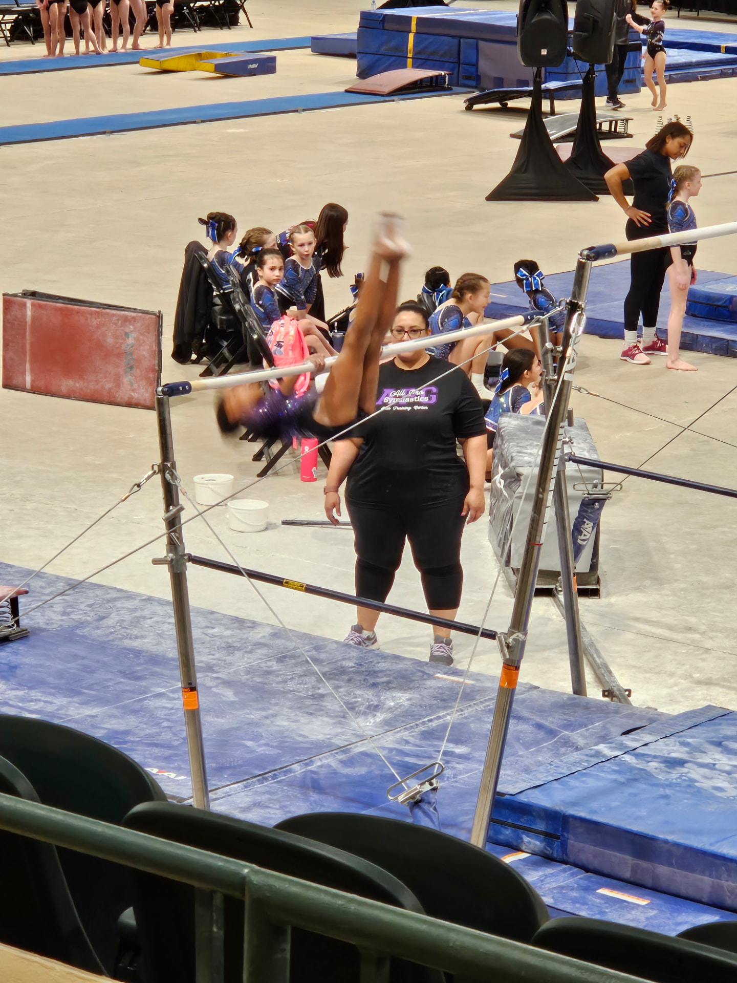 Gymnast competing on the uneven bars at a meet